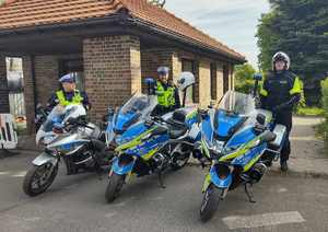 Na zdjęciu trzech policjantów ruchu drogowego, przed nimi motocykle służbowe.