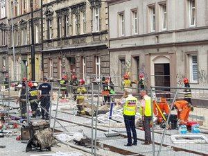 zdjęcie przedstawia dowódcę akcji policyjnej, policjantów oraz strażaków wykonujących czynności w pobliżu miejsca, gdzie doszło do eksplozji