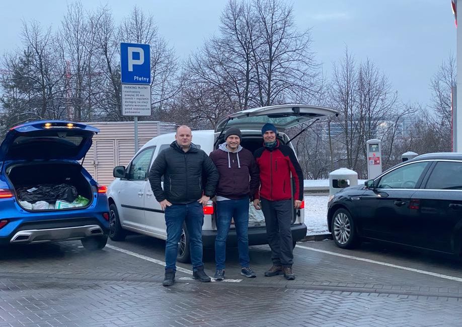 Dawid Zawiślak, Grzegorz Kołodziej i Grzegorz Strzelczyk stoją na parkingu przy samochodach