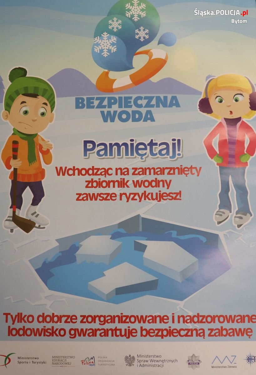 Zdjęcie przedstawia chłopca i dziewczynkę stojących nad taflą lodu  i napis Pamiętaj! Wchodząc na zamarznięty zbiornik wodny zawsze ryzykujesz! Tylko dobrze zorganizowane i nadzorowane lodowisko gwarantuje bezpieczną zabawę.