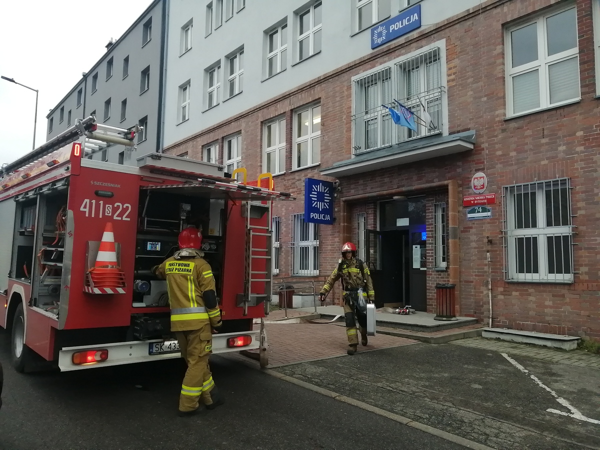 Na zdjęciu widzimy wóz strażacki i strażaków przed Komendą Miejską Policji w Bytomiu.