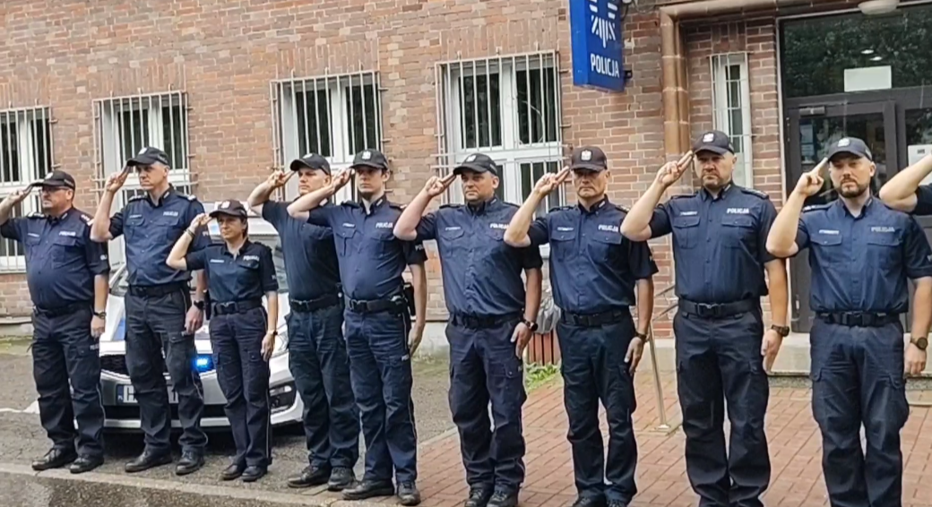 Na zdjęciu salutujący policjanci, ustawieni w szeregu przed budynkiem bytomskiej komendy.