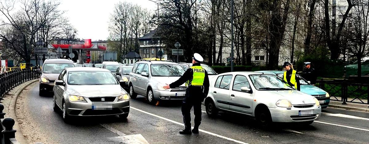 na zdjęciu policjanci drogówki stojący na jezdni przy samochodach, w trakcie badań trzeźwości