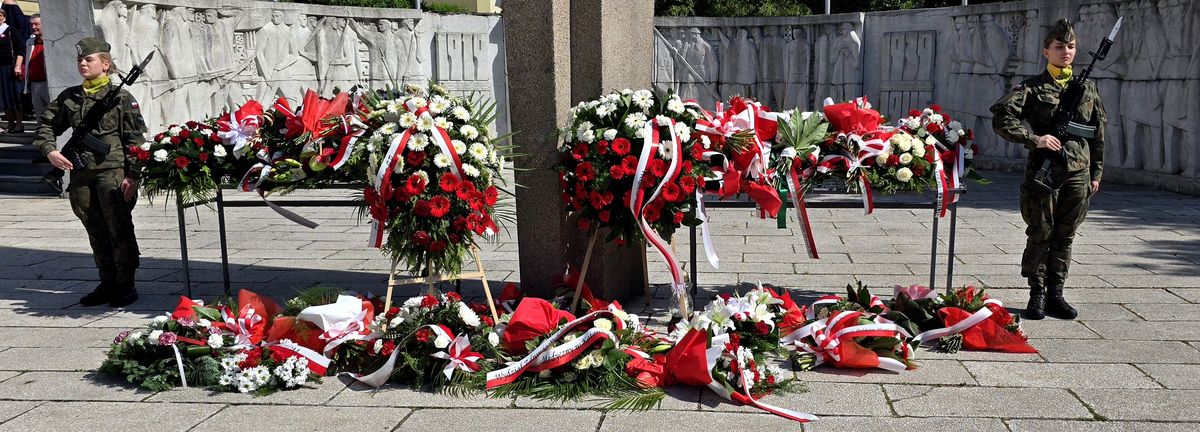na zdjęciu kwiaty złożone przed pomnikiem
