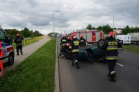 Strażacy zajmują się samochodem, który dachował.