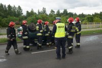 Policjant i strażacy znajdują się przy uszkodzonym aucie.