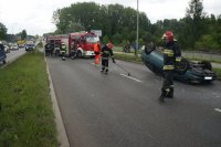 Miejsce dachowania osobowej toyoty, strażacy zamiatają szkoło z szyb auta.