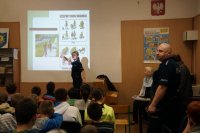 Policjantka pokazuje uczniom slajd dotyczący jazdy na rowerze.