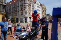 Dziewczynka siedzi na policyjnym motorze w asyście policjanta.