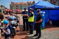 Trzech policjantów stoi przy namiocie tematycznym KMP Bytom, dziecko siedzi na motorze.