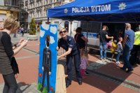 Policjantka asekuruje dziecko pozujące do zdjęcie przy makiecie Policjanta.