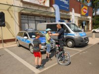 Policjant pomaga chłopcu założyć kask rowerowy.