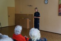 Seniorzy słuchają prelekcji policjantki.