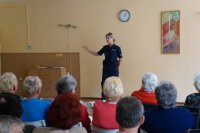 Seniorzy słuchają prelekcji policjantki.