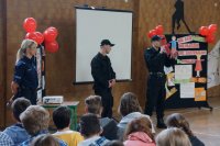 Policjant prowadzący pokaz samoobrony objaśnia uczniom techniki stosowane podczas obrony przed napastnikiem