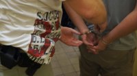 Policjant zakłada zatrzymanemu kajdanki
