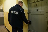 Umundurowany policjant stoi przed drzwiami