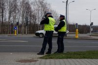 Policjanci drogówki kontrolują miernikiem prędkość kierowców stojąc przy drodze