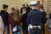 Policjant WRD objaśnia zasady a w tle uczestnicy konkursu