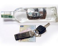 Na białym tle widać butelkę wódki, kluczyki samochodowe i dowód rejestracyjny.