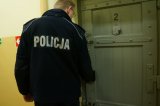 Policjant stoi przed drzwiami w pomieszczeniu dla osób zatrzymanych