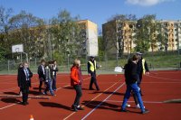 Policjanci na boisku szkolnym omawiają uczniom trasę przejazdu