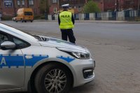 Policjant drogówki stoi przed radiowozem