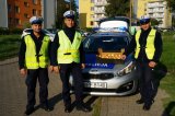 trzech policjantów stoi przy radiowozie