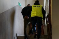 policjant z zatrzymanym wchodzi po schodach