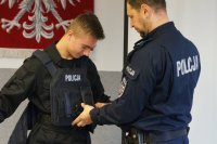 policjant ubiera w kamizelkę młodzieńca