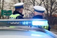 policjanci stoją za radiowozem