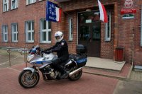 policjant na motocyklu stoi przed komendą