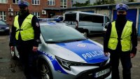 policjanci pozują przed radiowozem