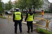 policjant i strażnik miejski stoi przy szkole