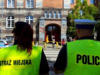 policjant i strażnik obserwują szkołę