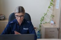 policjantka prowadzi prelekcję onlinę siedząc przed monitorem laptopa