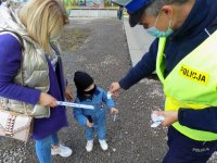 policjant daje dziecko odblaski