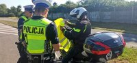 Policjanci ruchu drogowego wręczający koszulkę odblaskową motocykliście