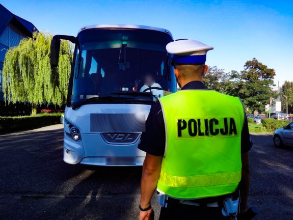 Umundurowany policjant ruchu drogowego stojący przed autobusem