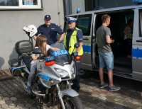 Policjanci pokazują motocykl i radiowóz dzieciom