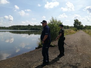 policjant i strażnik miejski przy stawie