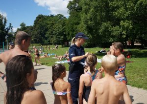 policjantka rozdaje odblaski dzieciom na basenie