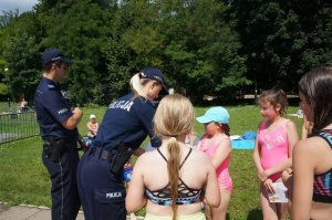 policjantka rozdaje odblaski dzieciom na basenie