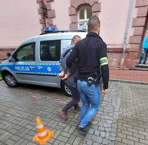 policjant prowadzi zatrzymanego