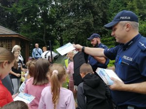 dzielnicowy rozdaje plany zajęć dzieciom