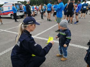 policjantka daje dziecku czapeczkę odblaskową