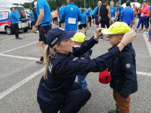 dzieci otrzymują czapeczki odblaskowe odcpolicjantki