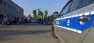 Policyjny radiowóz na parkingu gzie gromadzą się motocykliści