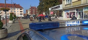 parada motocyklistów wjeżdża na rynek, zabezpiecza radiowóz drogówki