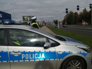 policjant ruchu drogowego przy radiowozie przy drodze